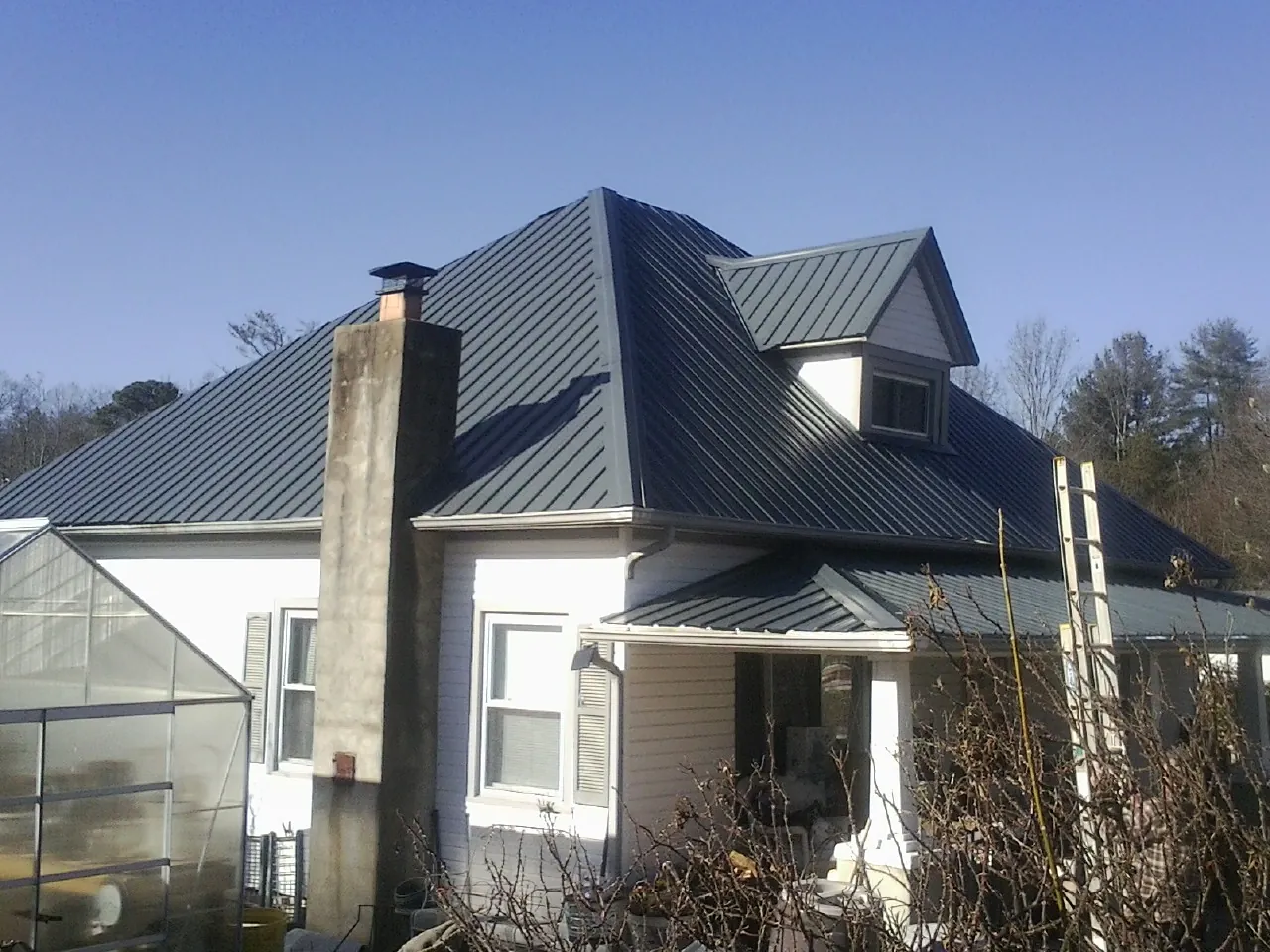 Dark blue standing seam metal roof on a white farmhouse with dormer — Slate & Tile Roof Repair by Roofing Brothers in Blacksburg