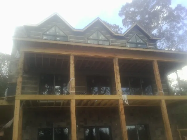 Dormers and porch framing on a large log home under construction — Roof Coating work by our crew in Blacksburg