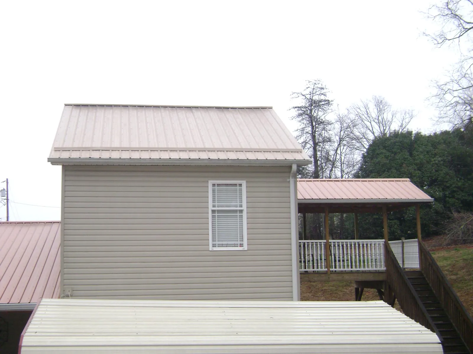 Tan metal roofs on a two story addition and attached porch, from a Roof Replacement job in Blacksburg