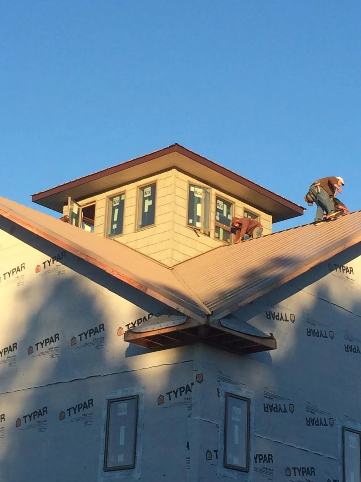 Roofers working around a rooftop cupola on a new metal roof at sunset — Roof Waterproofing in Blacksburg by Roofing Brothers